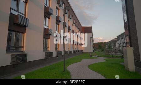 Sonnenbeschienener Weg In Friedlichem Innenhof. Gelassene Außenszene Mit Glühenden Fenstern Und Üppiger Vegetation. Stock-Clip Stockfoto