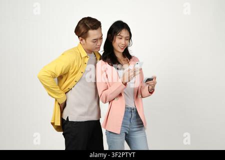 Porträt eines glücklichen asiatischen indonesischen Paares, das ein Smartphone und eine Kreditkarte auf einem isolierten Hintergrund hält. Stockfoto