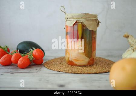 Eingemachte Gemüsesorten in einem Glas mit frischen Zutaten daneben Stockfoto