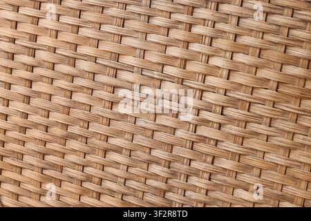 Nahaufnahme von natürlicher gewebter Rattan-Textur mit kunstvollem Muster und warmen Brauntönen, die Oberfläche zeigt warme Brauntöne und schafft eine rus Stockfoto