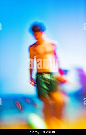 Junger Mann bewegt sich am Strand mit extremen Hitzeunschärfe und lebendigen Farben Stockfoto