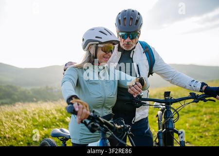 Ältere Biker machen eine Pause während der Radtour und überprüfen ihre Leistung auf der Smartwatch. Stockfoto