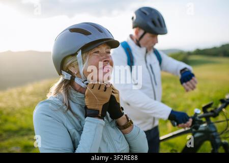 Ältere Biker machen eine Pause während der Radtour und überprüfen ihre Leistung auf der Smartwatch. Stockfoto