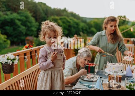Familie genießt Geburtstagskuchen während einer Feier im Freien. Stockfoto