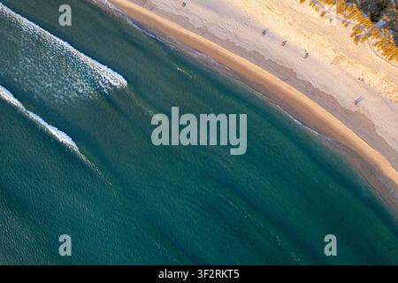 Wunderschöne Küstenlandschaft, die von oben zeigt, wie Meereswellen an einem breiten Sandstrand brechen Stockfoto