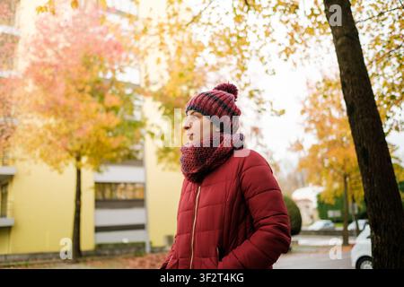 Frau steht im Freien in roter Jacke und Strickware während des Herbstes Stockfoto