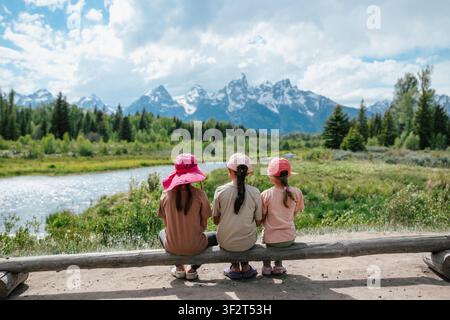 Drei Kinder sitzen zusammen und blicken auf die Berge. Stockfoto