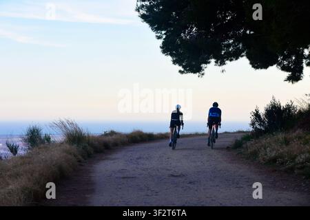 Zwei Radfahrer fahren gemeinsam entlang eines Weges in der Dämmerung. Stockfoto