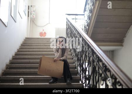 Junge schwarze Frau, die ein Pappschild auf der Treppe hält Stockfoto