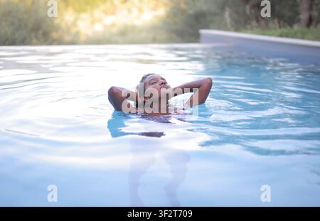 Gelassene junge Frau entspannt sich in einem Schwimmbecken Stockfoto