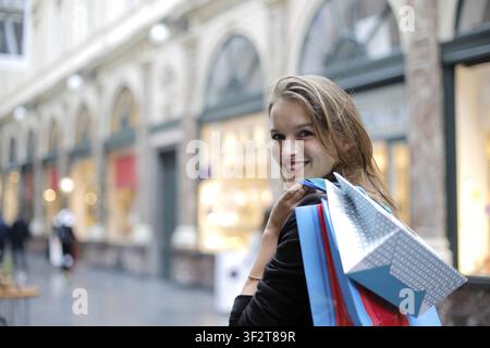 Glückliche junge Frau mit Einkaufstüten schaut zurück Stockfoto