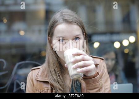 Frau mit blauen Augen trinkt Kaffee in einem Café Stockfoto