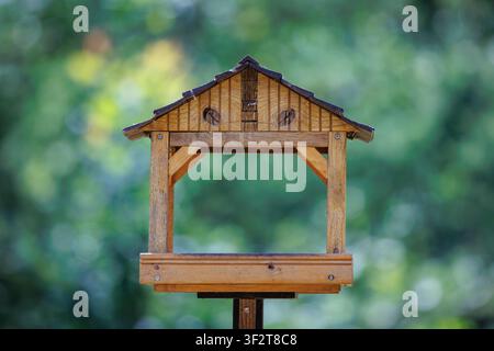 Ein leerer hölzerner Vogelhäuschen in einem Garten mit einem verschwommenen grünen Hintergrund Stockfoto