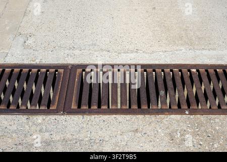 Metallischer Sturmabflussgitter auf urbanem Pflaster. Regenwasserbewirtschaftungsinfrastruktur. Minimal. Stockfoto