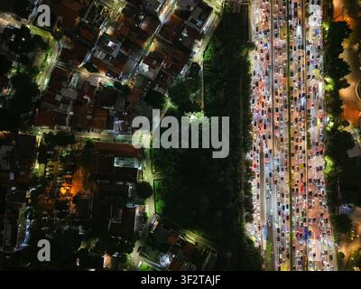 Luftaufnahme des Semanggi-Kreuzungsbereichs bei Nacht, die starke Verkehrsstauungen auf der Autobahn zeigt, umgeben von städtischen Gebäuden und Bäumen in Setiabudi Stockfoto