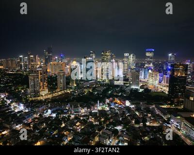 Luftaufnahme des beleuchteten Semanggi-Kreuzungsbereichs und der dichten Skyline von Jakarta bei Nacht mit leuchtenden Wolkenkratzern und urbanen Lichtern in Setiabudi, Jak Stockfoto