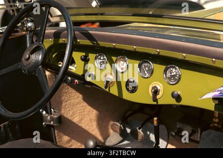 Berlin, Deutschland - 3. Mai 2026. Detaillierte Ansicht eines grünen Metalldashboards, analoger Instrumente, Zündschalter, Lenkrads und Pedale in einem Res Stockfoto