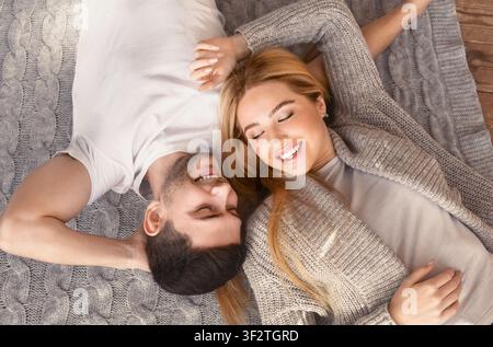 Junger Mann und Frau liegen zusammen auf gestricktem Plaid, Blick über den Kopf Stockfoto