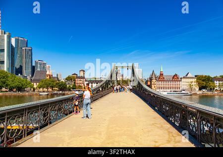Frankfurt, Deutschland - 15. Mai 2026: Touristen und Menschen, die auf der Eiserner Steg-Fußgängerbrücke über den Main spazieren, mit der Stadtsilhouette im Hintergrund Stockfoto