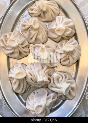 Traditionelle georgische Khinkali-Teigtaschen auf einem Tablett mit schwarzem Pfeffer. Authentische kaukasische Küche. Stockfoto