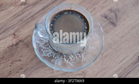 Tasse Kaffee in einem Glasbecher auf einer Holzoberfläche, Ansicht von oben Stockfoto