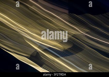 Dynamische abstrakte ICM-Komposition mit goldenen Lichtspuren und diagonaler Bewegungsunschärfe vor dunklem Hintergrund. Fließende Energie und leuchtende Texturen c Stockfoto