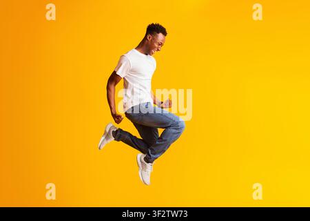 Fröhlich schreiender junger afroamerikanischer Mann springt Stockfoto