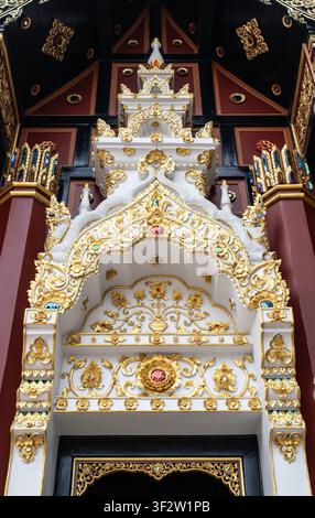 Chiang Mai, Thailand - 20. Juli 2026: Verzierter vergoldeter Stuck-Tempel-Eingang mit Lanna-Stil-Gold- und Weißschnitzereien am buddhistischen Tempel Stockfoto