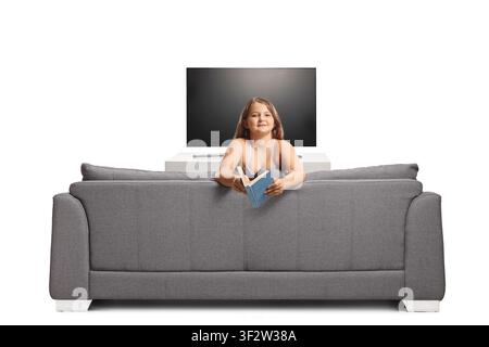 Mädchen lehnt sich auf ein Sofa und hält ein offenes Buch, isoliert auf weißem Hintergrund Stockfoto
