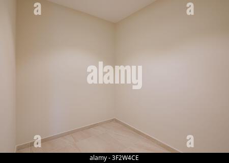 Leerer beiger Innenraum mit Fliesenboden, sanftem natürlichem Licht, sauberen neutralen Wänden, unmöbliertem Layout, minimalistischem Stil, ruhiger Wohnraum für Stockfoto