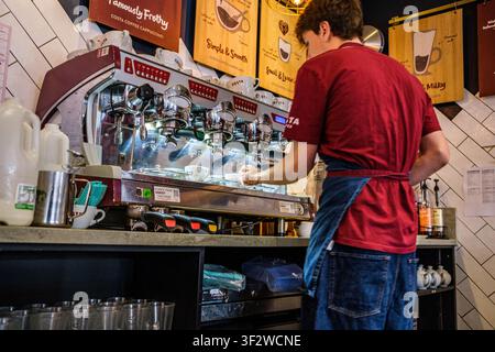 Leatherhead Surrey UK, 20. Juli 2026, Nahaufnahme eines Barista mit dem Rücken zur Kamera, der ein heißes Kaffeigetränk für einen Kunden bei Costa zubereitet Stockfoto