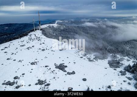 Luftbild des schneebedeckten Gipfels der Hornisgrinde mit einem Fernmeldeturm und einer Windkraftanlage, umgeben von Winterwald im Schwarzwald, Seebach, B Stockfoto