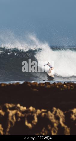 HALEIWA, NORTH SHORE, HAWAII - 19. JANUAR 2022: Eine Frau fährt ein Longboard unter einer großen brechenden Welle an der North Shore. Stockfoto
