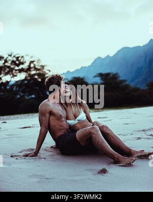 Ein junges Paar geht Hand in Hand entlang eines abgelegenen Strandes an der Waianae-Küste von Oahu, Hawaii. Stockfoto