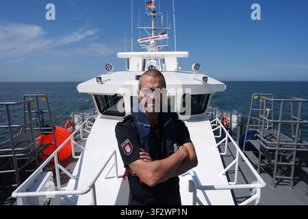 PRODUKTION - 13. Juli 2026, Niedersachsen, Cuxhaven: Alexander Wiegleb, Patrouillenleiter der Hamburger Wasserschutzpolizei, steht auf dem Deck des seetüchtigen Küstenpatrouillenboots WS 1 ·Bürgermeister Brauer· während einer Patrouille auf der Nordsee. Der Zuständigkeitsbereich des Wasserschutzpolizeireviers 4 (WSPK 4) erstreckt sich entlang der Elbe über 77 Seemeilen von Tonne 105/106 vor Stade bis zur Tonne E 3, etwa 15 Seemeilen südlich von Helgoland, sowie das Hamburger Wattenmeer mit seinen Inseln Neuwerk, Scharhörn und Nigehörn. Foto: Marcus Brandt/dpa Stockfoto