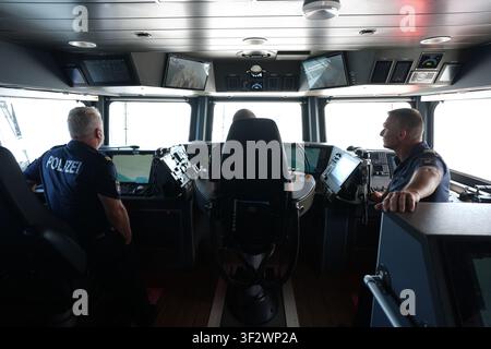 PRODUKTION - 13. Juli 2026, Niedersachsen, Cuxhaven: Maik Mante (von rechts nach links), ein Beamter der Hamburger Wasserschutzpolizei, Alexander Wiegleb, Patrouillenleiter, und Stephan Amberge, Ingenieur, stehen auf der Brücke des seetüchtigen Küstenpatrouillenboots WS 1 ·Bürgermeister Brauer· während einer Patrouille in der Nordsee. Der Zuständigkeitsbereich des Wasserschutzpolizeireviers 4 (WSPK 4) erstreckt sich entlang der Elbe über 77 Seemeilen von Tonne 105/106 nahe Stade bis zur Tonne E 3, etwa 15 Seemeilen südlich von Helgoland, sowie das Hamburger Wattenmeer mit seinen Inseln Neuwerk, Scharhörn und Nigehörn. Foto: Marcus Brandt/dp Stockfoto