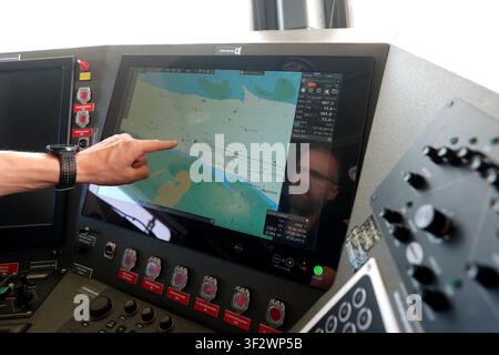 PRODUKTION - 13. Juli 2026, Niedersachsen, Cuxhaven: Alexander Wiegleb, Patrouillenleiter der Hamburger Wasserschutzpolizei, sitzt während einer Patrouille auf der Nordsee auf der Brücke des seetüchtigen Küstenpatrouillenboots WS 1 ·Bürgermeister Brauer· am Steuer und betrachtet eine digitale Seekarte. Der Zuständigkeitsbereich des Wasserschutzpolizeireviers 4 (WSPK 4) erstreckt sich entlang der Elbe über 77 Seemeilen von Tonne 105/106 nahe Stade bis zur Tonne E 3, etwa 15 Seemeilen südlich von Helgoland, sowie das Hamburger Wattenmeer mit seinen Inseln Neuwerk, Scharhörn und Nigehörn. Foto: Marcus Brandt/dpa Stockfoto