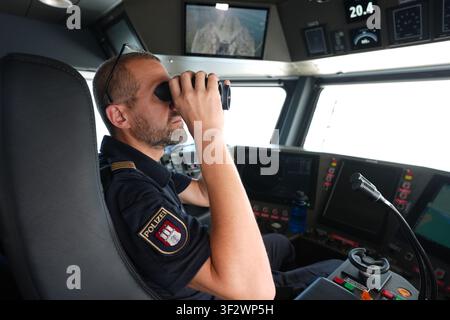 PRODUKTION - 13. Juli 2026, Niedersachsen, Cuxhaven: Alexander Wiegleb, Patrouillenleiter der Hamburger Wasserschutzpolizei, blickt durch ein Fernglas vom Steuerstand des seetüchtigen Küstenpatrouillenboots WS 1 ·Bürgermeister Brauer· auf der Brücke während einer Patrouille auf der Nordsee. Der Zuständigkeitsbereich des Wasserschutzpolizeireviers 4 (WSPK 4) erstreckt sich entlang der Elbe über 77 Seemeilen von Tonne 105/106 bei Stade bis zur Tonne E 3, etwa 15 Seemeilen südlich von Helgoland, sowie das Hamburger Wattenmeer mit seinen Inseln Neuwerk, Scharhörn und Nigehörn. Foto: Marcus Brandt/dpa Stockfoto