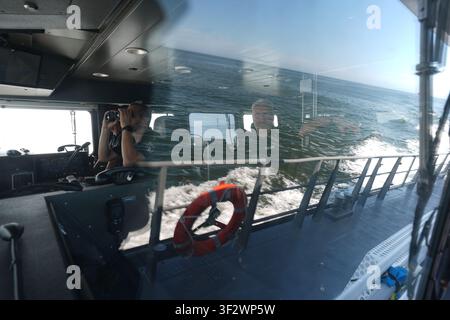 PRODUKTION - 13. Juli 2026, Niedersachsen, Cuxhaven: Alexander Wiegleb (links), Patrouillenleiter der Hamburger Wasserpolizei, schaut durch ein Fernglas neben Stephan Amberge (rechts), Ingenieur, auf der Brücke am Ruder des seetüchtigen Küstenpatrouillenboots WS 1 ·Bürgermeister Brauer· während einer Patrouille in der Nordsee. Das Patrouillengebiet des Wasserpolizeireviers 4 (WSPK 4) erstreckt sich entlang der Elbe über 77 Seemeilen von Tonne 105/106 nahe Stade bis zur Tonne E 3, etwa 15 Seemeilen südlich von Helgoland, sowie das Hamburger Wattenmeer mit seinen Inseln Neuwerk, Scharhörn und Nigehörn. Foto: Marcus Br Stockfoto