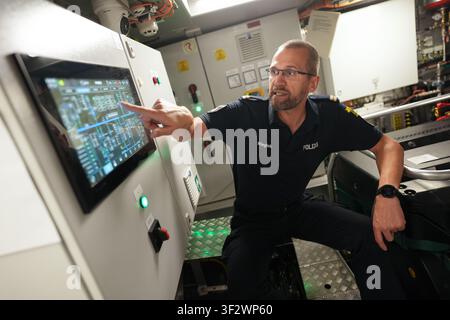 PRODUKTION - 13. Juli 2026, Niedersachsen, Cuxhaven: Alexander Wiegleb, Patrouillenleiter der Hamburger Wasserschutzpolizei, überprüft den Hybridmodus und den Batteriestand im Maschinenraum des seetüchtigen Küstenpatrouillenboots WS 1 ·Bürgermeister Brauer· kurz vor einer Patrouille auf der Nordsee. Das Patrouillengebiet des Wasserschutzpolizeireviers 4 (WSPK 4) erstreckt sich entlang der Elbe über 77 Seemeilen von Tonne 105/106 bei Stade bis zur Tonne E 3, etwa 15 Seemeilen südlich von Helgoland, sowie das Hamburger Wattenmeer mit seinen Inseln Neuwerk, Scharhörn und Nigehörn. Foto: Marcus Brandt/dpa Stockfoto