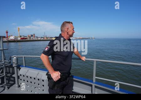PRODUKTION - 13. Juli 2026, Niedersachsen, Cuxhaven: Maik Mante, ein Beamter der Hamburger Wasserschutzpolizei, steht auf dem Deck des seetüchtigen Küstenpatrouillenboots WS 1 ·Bürgermeister Brauer· während einer Patrouille in der Nordsee. Der Zuständigkeitsbereich des Wasserschutzpolizeireviers 4 (WSPK 4) erstreckt sich entlang der Elbe über 77 Seemeilen von Tonne 105/106 nahe Stade bis zur Tonne E 3, etwa 15 Seemeilen südlich von Helgoland, sowie das Hamburger Wattenmeer mit seinen Inseln Neuwerk, Scharhörn und Nigehörn. Foto: Marcus Brandt/dpa Stockfoto