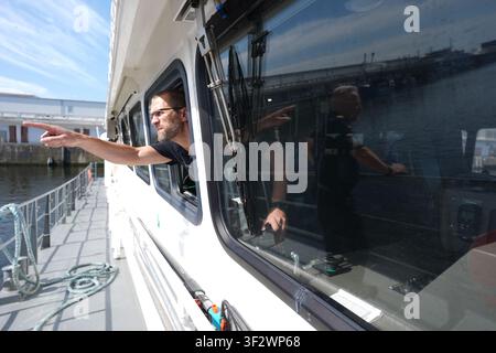 PRODUKTION - 13. Juli 2026, Niedersachsen, Cuxhaven: Alexander Wiegleb, Patrouillenleiter der Hamburger Wasserschutzpolizei, blickt aus einem Fenster auf der Brücke des seetüchtigen Küstenpatrouillenboots WS 1 ·Bürgermeister Brauer·, während es in die Elbe entlassen wird. Der Zuständigkeitsbereich des Wasserschutzpolizeireviers 4 (WSPK 4) erstreckt sich entlang der Elbe über 77 Seemeilen von Tonne 105/106 nahe Stade bis zur Tonne E 3, etwa 15 Seemeilen südlich von Helgoland, sowie das Hamburger Wattenmeer mit seinen Inseln Neuwerk, Scharhörn und Nigehörn. Foto: Marcus Brandt/dpa Stockfoto