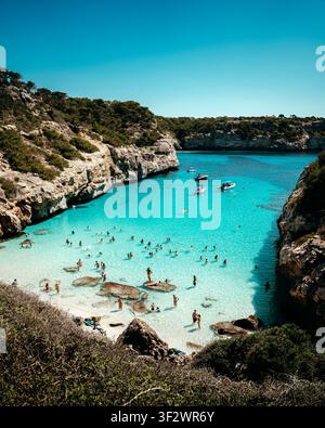 Mallorca, Spanien - 15. September 2023: Blick auf Cala des Moro mit türkisfarbenem Wasser, felsigen Klippen und Menschen, die unter einem c schwimmen und am Strand entspannen Stockfoto