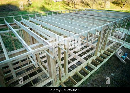 Holzrahmenhaus im Bau, Dachbalken und Bodenstruktur auf Pfahlfundament montiert, unfertiges Holzgebäude in ländlicher Landschaft, Luftperspektive des Öko-Hausprojekts Stockfoto