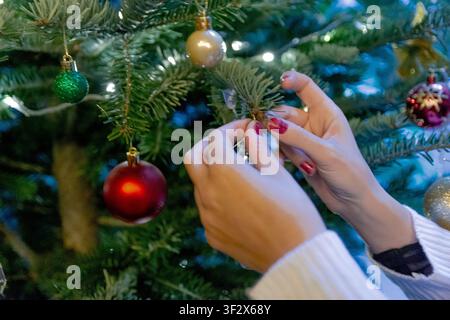 Person, die einen Weihnachtsbaum mit Ornamenten zu Weihnachten schmückt Stockfoto