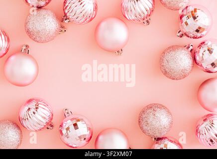 Rosa Weihnachtskugeln rahmen auf pastellrosa Hintergrund mit Kopierraum. Weihnachts- und Neujahrskonzept. Kreativer festlicher Feiertags-Hintergrund. Stockfoto