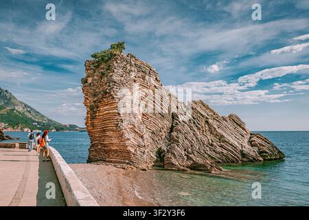 23. Mai 2026, Becici, Montenegro: Adriaküste mit einzigartigen geschichteten Felsformationen an einem sonnigen Tag mit wandernden Touristen, zeigt Geol Stockfoto