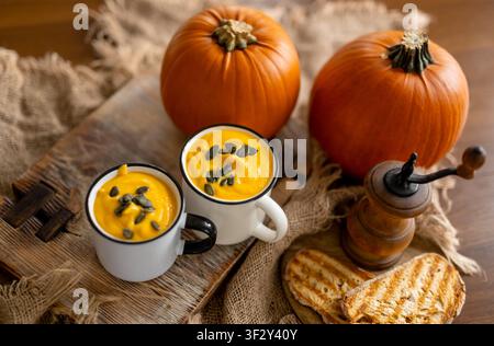 Oberansicht von Kürbissuppe und Kürbissen in Tassen mit einer rustikalen Komposition Stockfoto