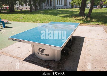 24. Mai 2026, Cetinje, Montenegro: Blauer Cornilleau-Freiluft-Tischtennis-Tisch, der in einem sonnigen öffentlichen Park steht und Erholung und Sport bietet Stockfoto