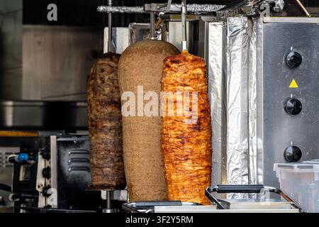 vertikale Rotisserie-Spieße beladen mit Schichten aus gewürztem Fleisch für Döner Kebab Stockfoto